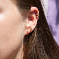 Close-up of an ear wearing gold hoop earrings with a blurred background - seolgold