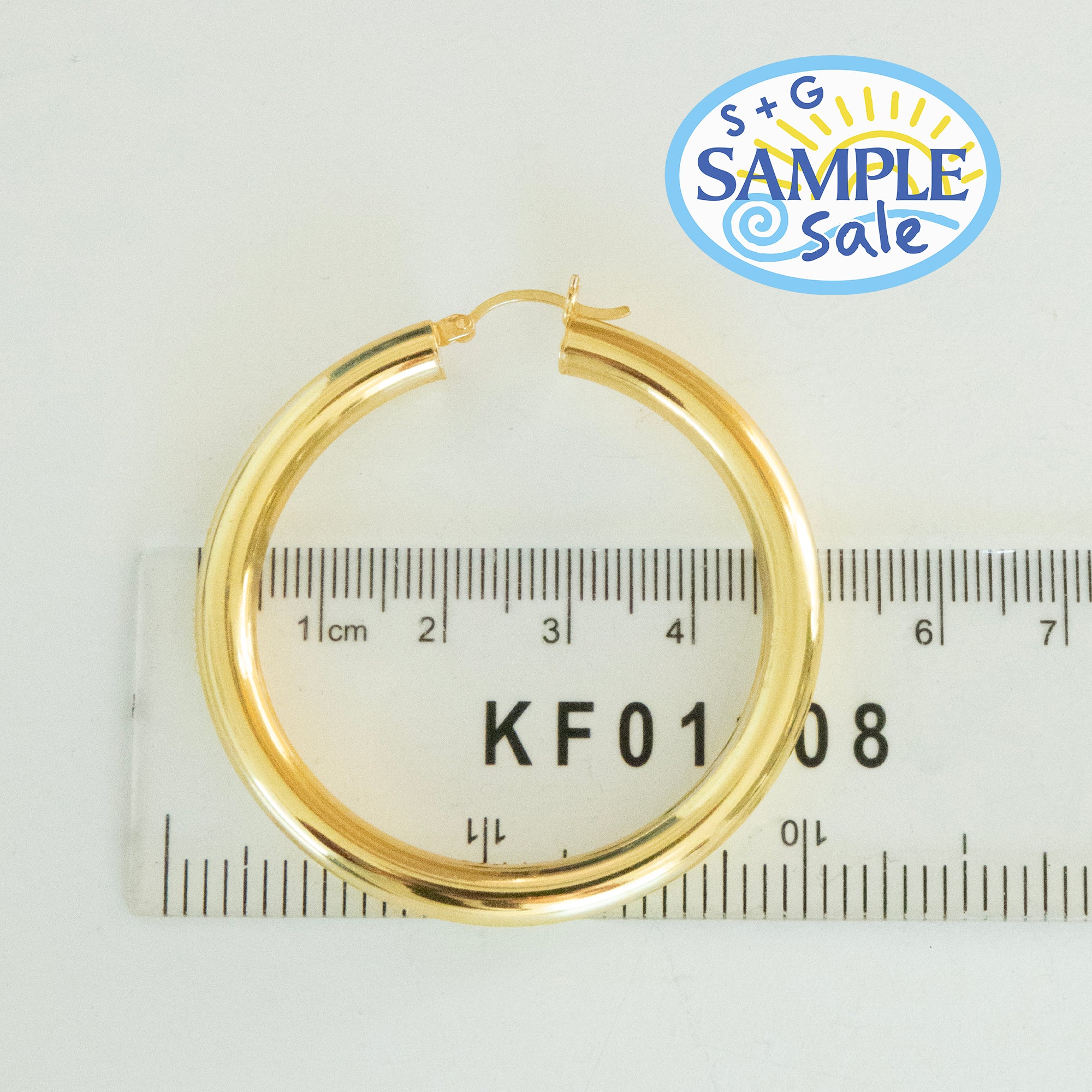 Gold hoop earring on a ruler with 'S+G Sample Sale' logo in the corner - seolgold