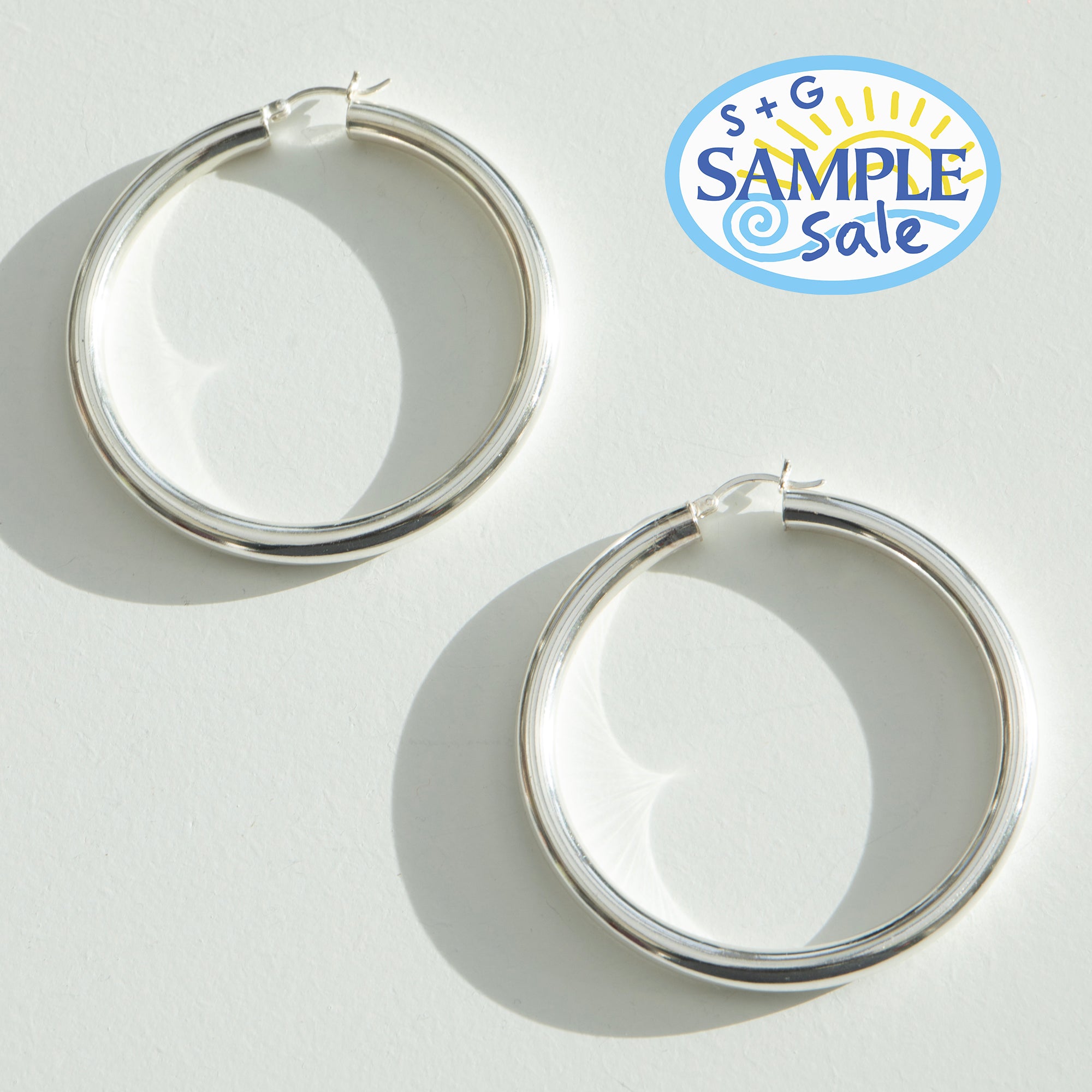 Silver hoop earrings on a light gray background with 'S+G Sample Sale' logo - seolgold