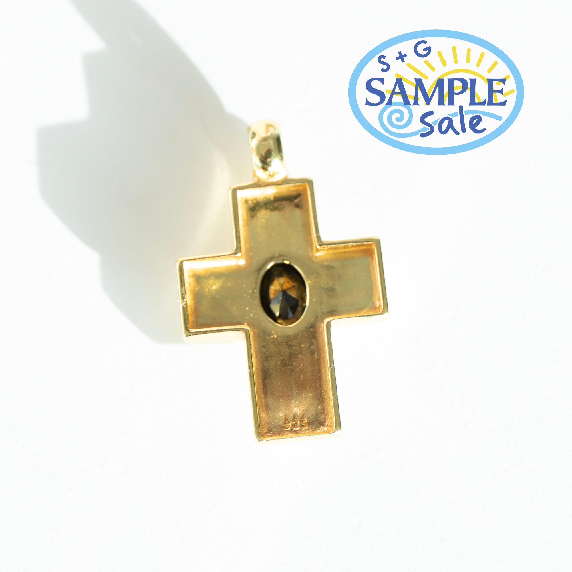 Gold cross pendant with a central gemstone on a white background, featuring a 'Sample Sale' label.