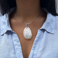 Necklace with a shell pendant worn by a person in a light blue shirt - seolgold