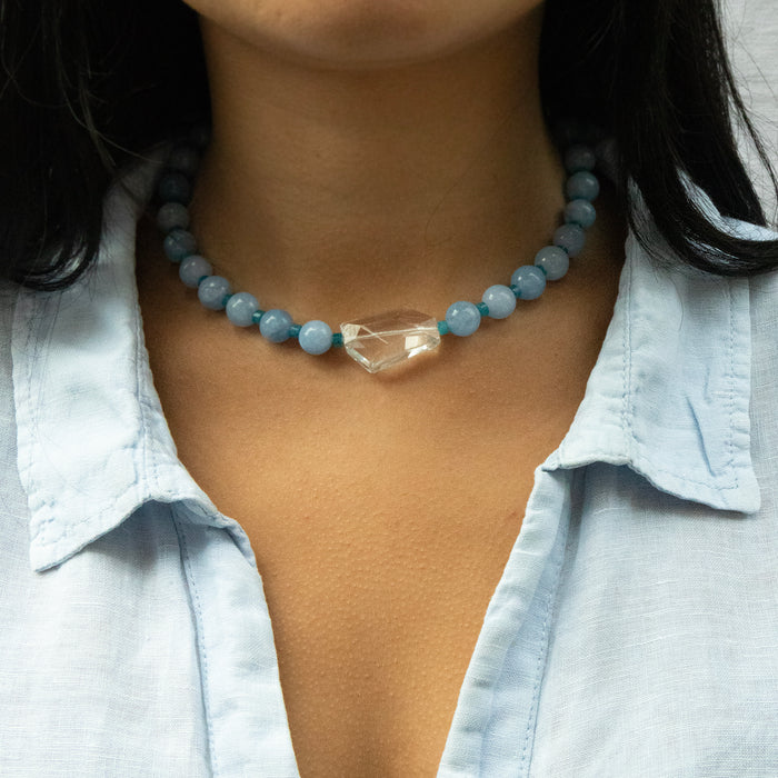 Necklace with blue beads and a clear crystal on a person wearing a light blue shirt - seolgold