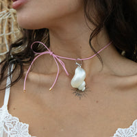 Close-up of a necklace with a large white pendant on a person wearing a white lace top - seolgold
