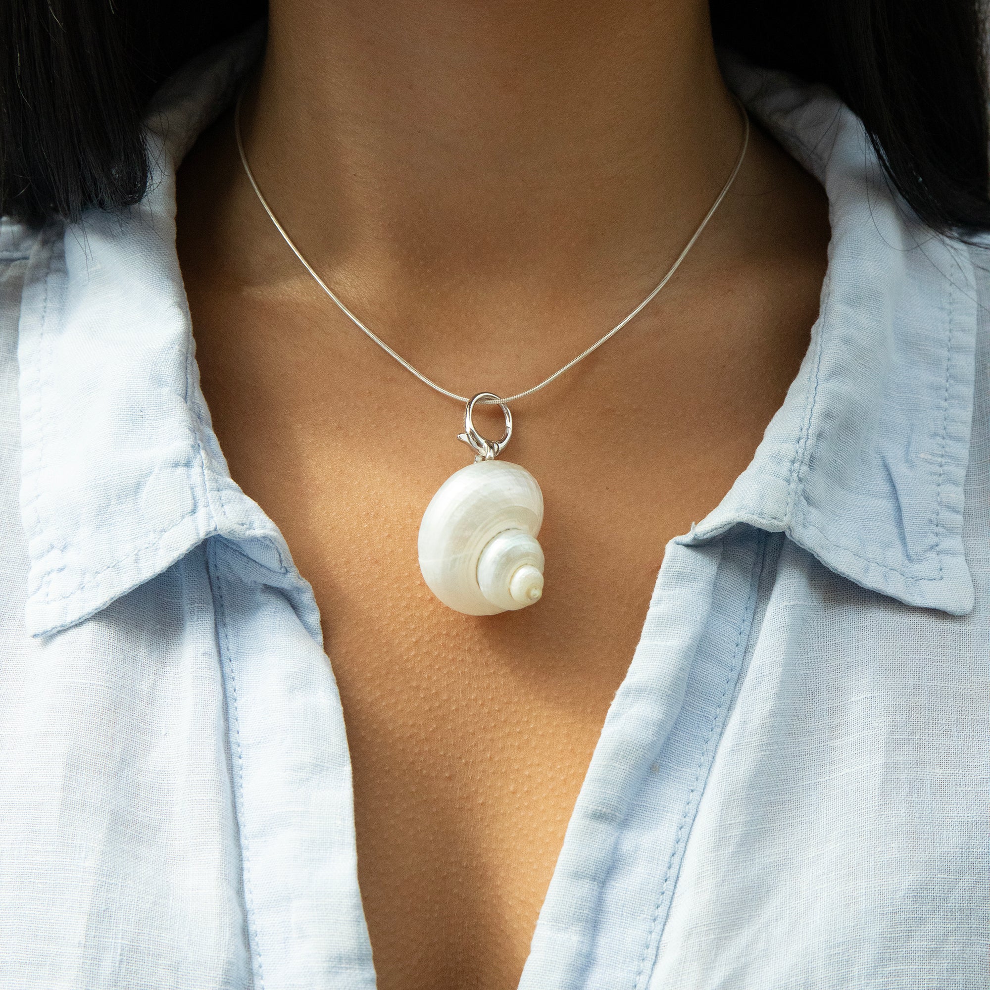 Necklace with a shell pendant worn by a person wearing a light blue shirt - seolgold
