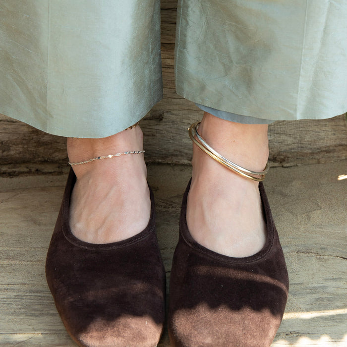 Brown suede shoes worn with light-colored pants on a wooden floor wearing anklets  - seolgold