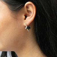 Close-up of an ear wearing a star-shaped earring with dark hair - Seol Gold