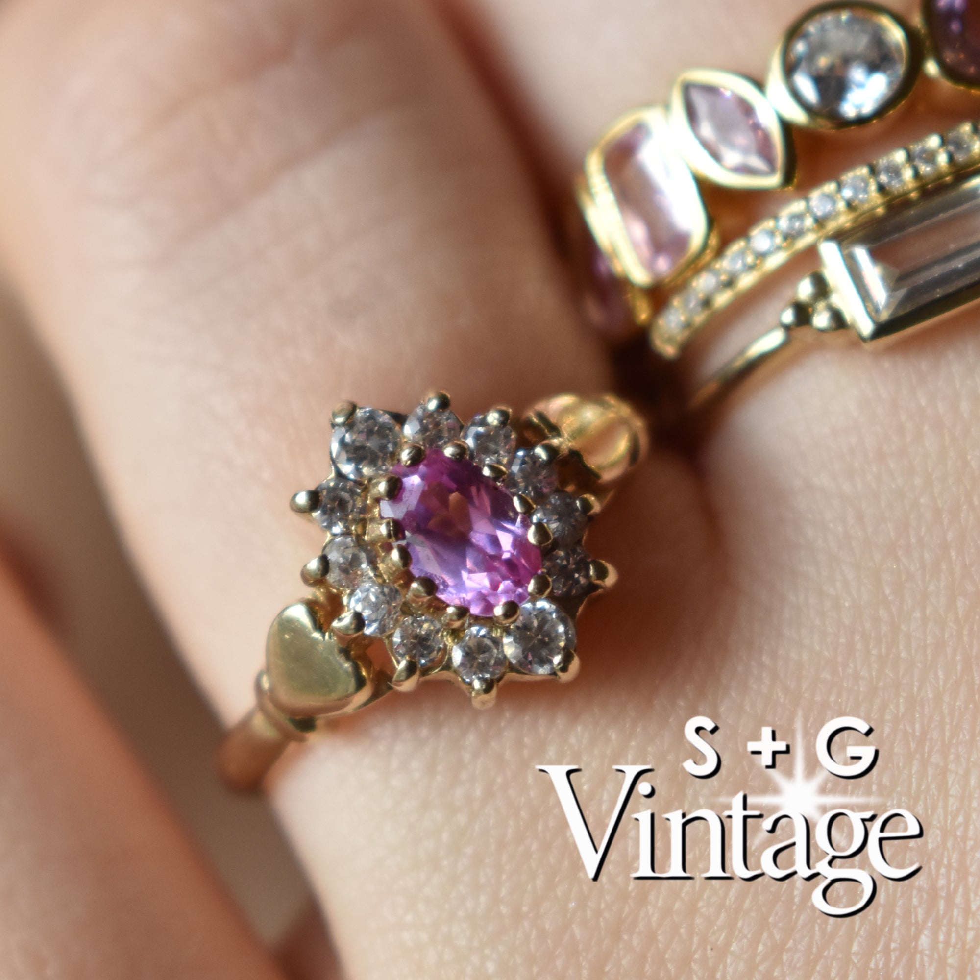 Close-up of a gold ring with a purple gemstone on a person's finger, branded 'S + G Vintage' - seolgold