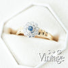 Gold ring with a blue gemstone and diamond accents on a white hexagonal stand, branded 'S + G Vintage' - seolgold
