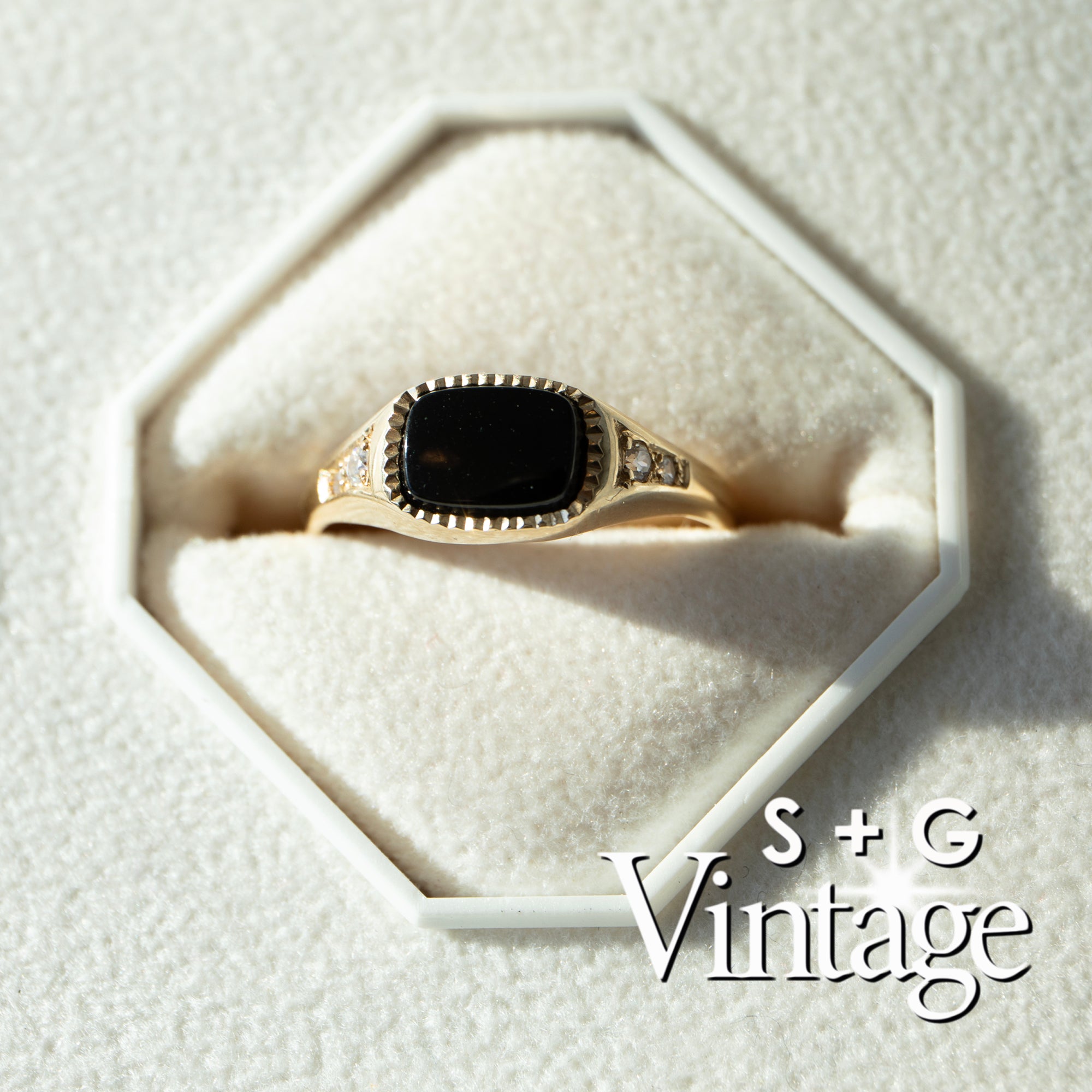 Gold ring with a black stone on a white textured surface, branded 'S + G Vintage' - seolgold