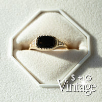Gold ring with a black stone on a white textured surface, branded 'S + G Vintage' - seolgold