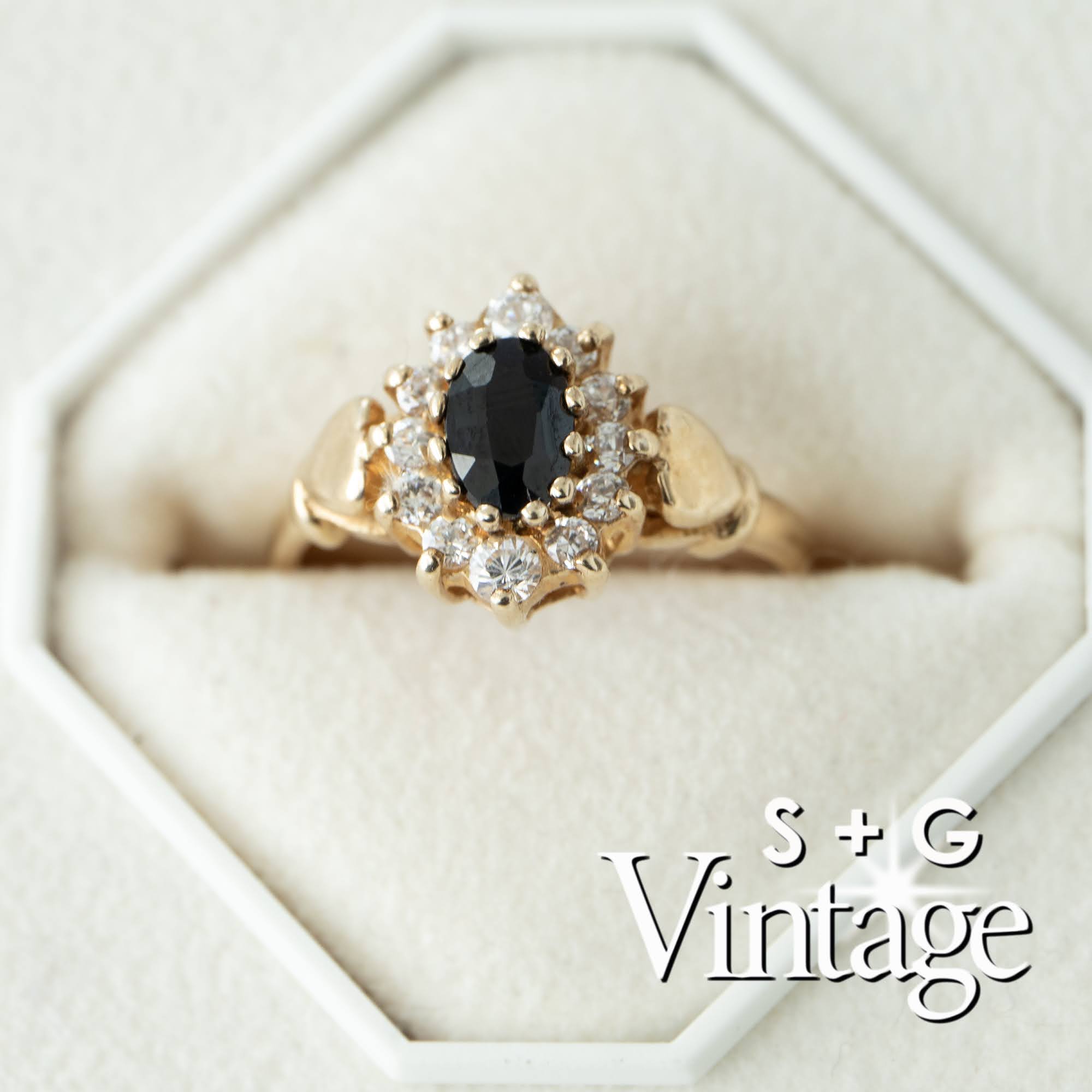 Gold ring with a black gemstone and diamonds on a white hexagonal stand, branded 'S + G Vintage' - seolgold