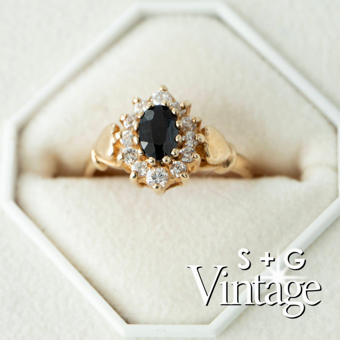 Gold ring with a black gemstone and diamonds on a white hexagonal stand, branded 'S + G Vintage' - seolgold