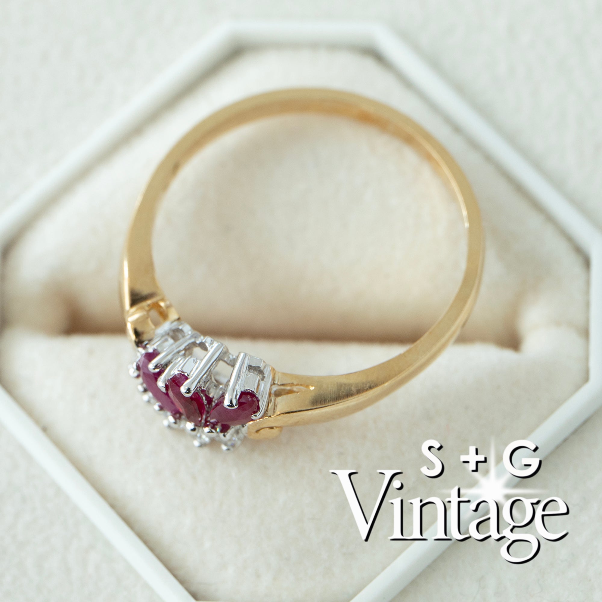 Gold ring with red gemstones on a white hexagonal stand, featuring 'S + G Vintage' branding - seolgold