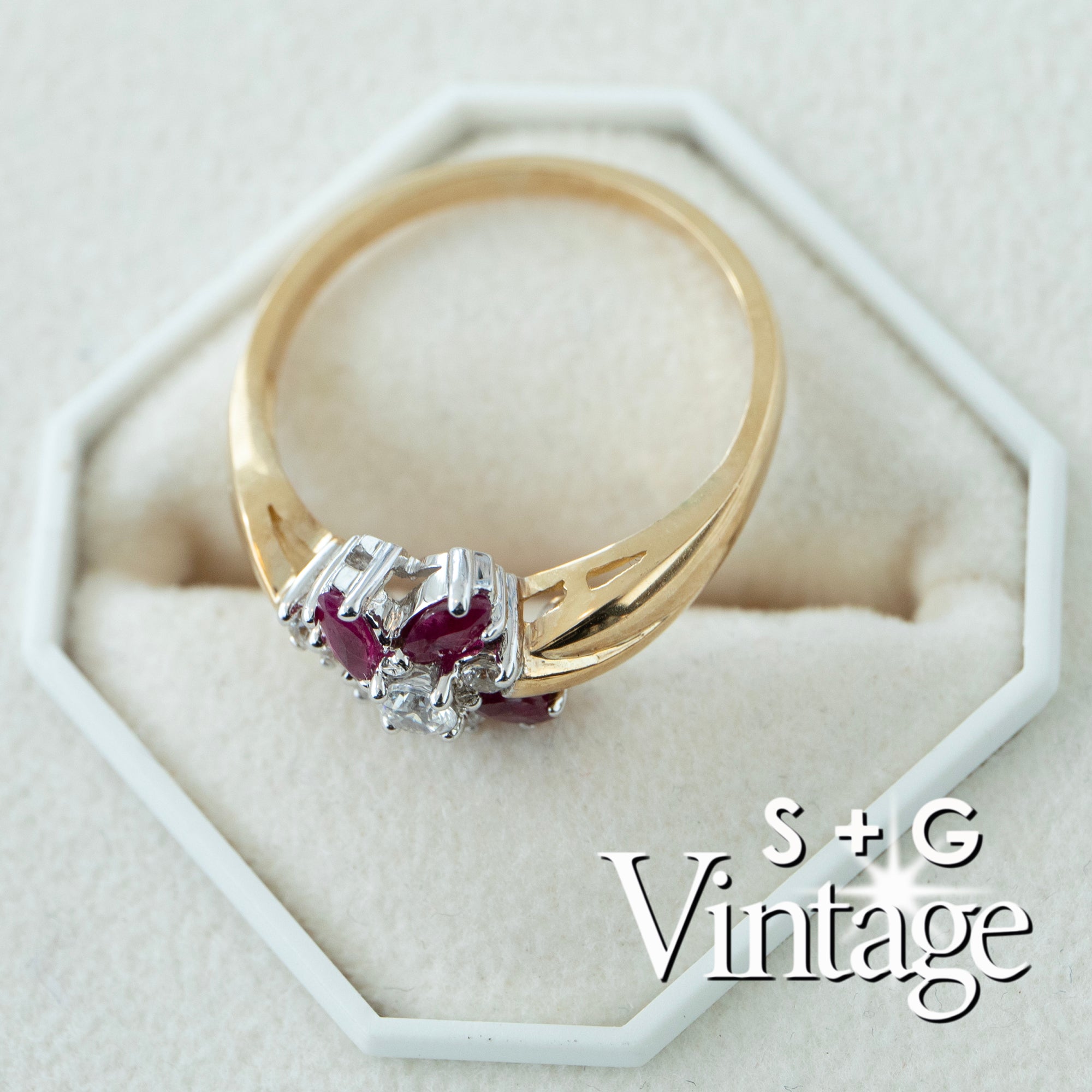 Gold ring with red gemstones and diamonds on a white hexagonal stand, branded 'S + G Vintage' - seolgold