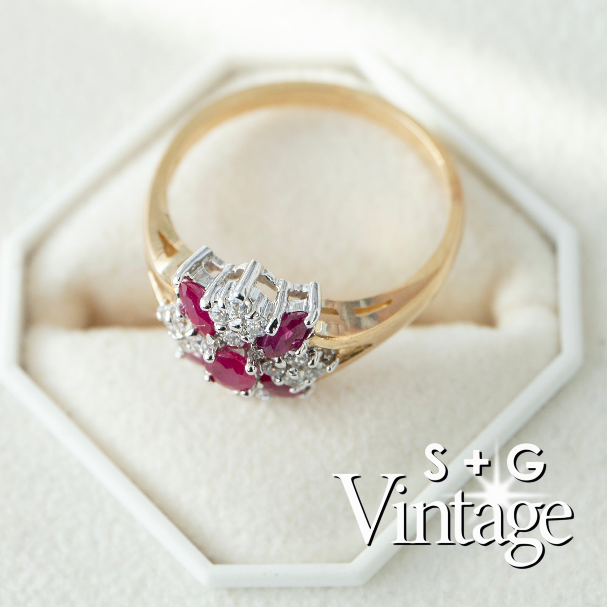 Gold ring with red gemstones and diamonds on a white hexagonal stand, branded 'S + G Vintage' - seolgold