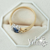 Gold ring with a blue gemstone on a white hexagonal stand, featuring 'S + G Vintage' branding - seolgold
