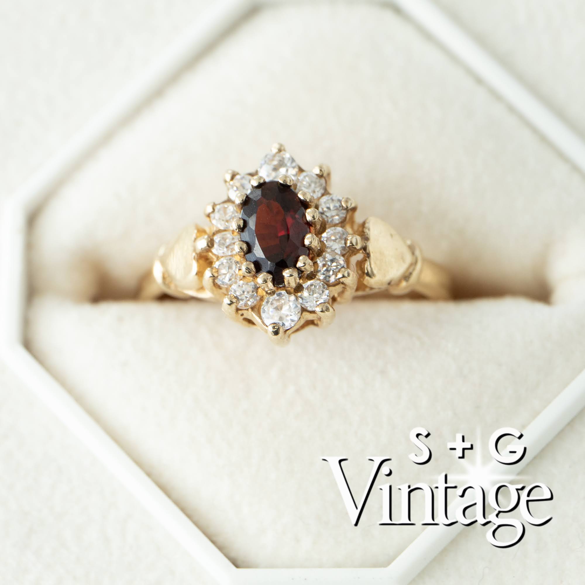 Gold ring with a garnet stone and diamond accents in a white box, branded 'S + G Vintage' - seolgold